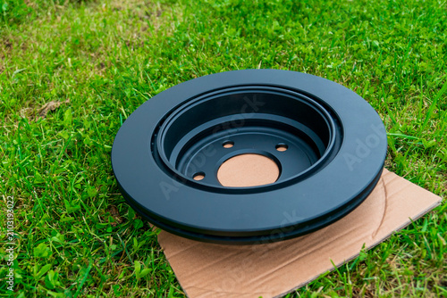 Obraz na płótnie Black brake rotor on cardboard in green grass during daytime