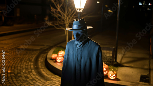 Spooky Halloween night scene with shadowy figure under streetlamp