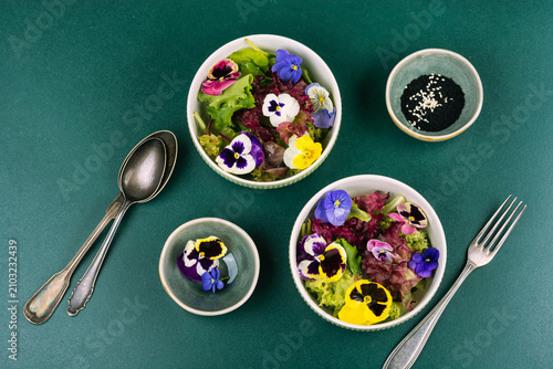 Organic lettuce salad decorated with edible pansy flowers