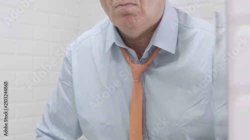 Blurred Shooting with a Borred Businessman in the Mirror Wearing a Blue Shirt and Untying a Tie from His Neck.