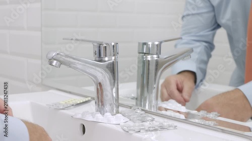 Blurred Shooting with a Sick and Suffering Man in Front of the Bathroom Mirror taking from the Sink Medical Pills.