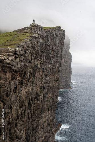 Lone Tourist Standing at the Edge of Towering Traelanipa Cliffs, Faroe Islands