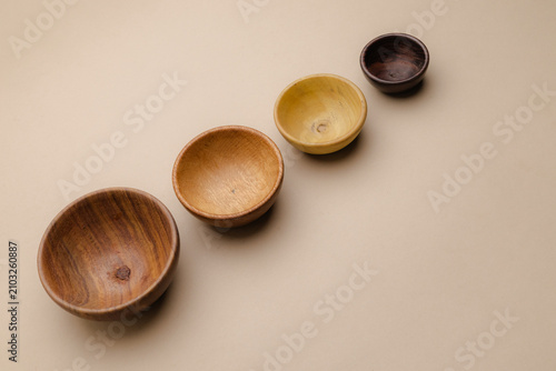 Fotografie Four small natural wooden bowls with varying shades sit diagonally on a neutral