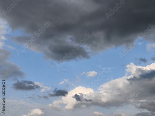 Blue sky with contrasting bright white cumulus and dark rain clouds