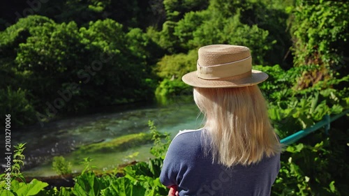 Woman in straw hat overlooking Blue Eye spring in Albania