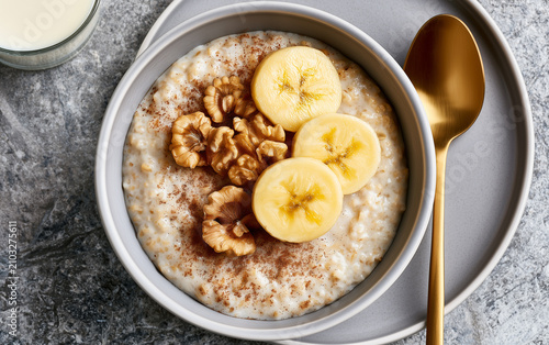 Banana walnut oatmeal breakfast healthy creamy fresh nutritious gold spoon gray plate delicious morning meal