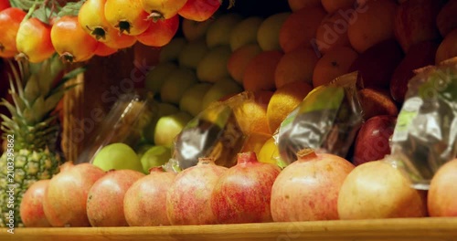 Vibrant assortment of fresh produce arranged at market display including red apples, rowan berries, pineapple, grapes in warm natural lighting.