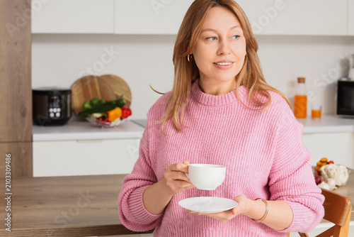 Beautiful woman with cup of coffee in kitchen