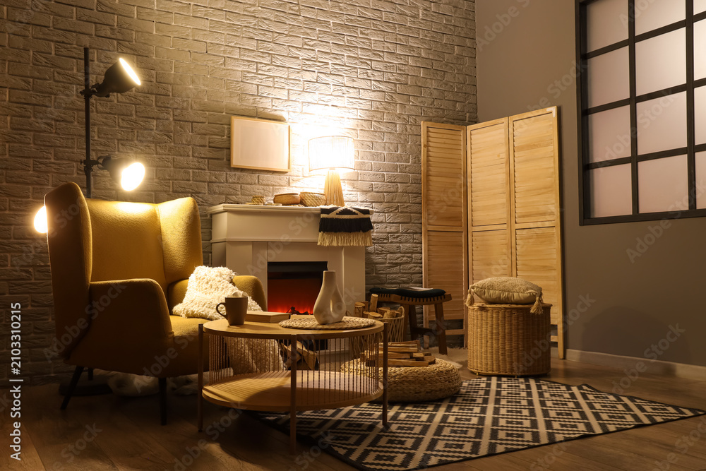 Obraz premium Interior of living room with fireplace, armchair and glowing lamps