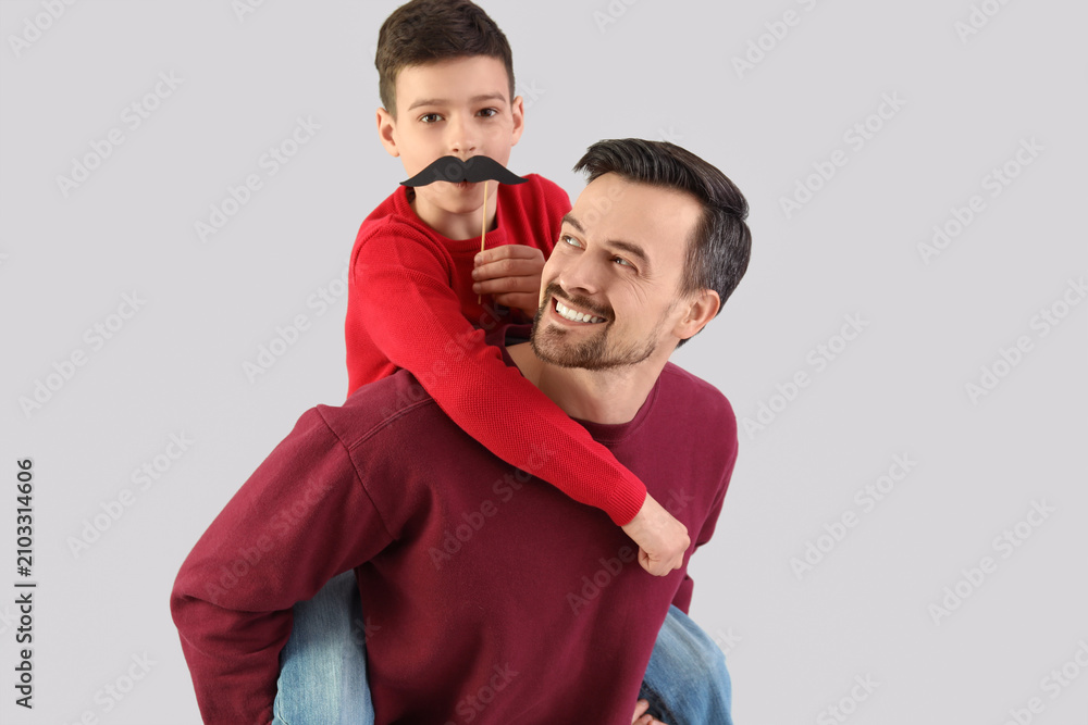 Obraz premium Portrait of father and his little son with paper mustache on light background
