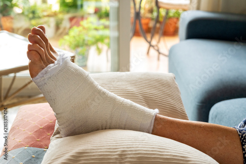 Cuadro en lienzo Close up of bandaged foot elevated on pillows during home recovery, ankle injury