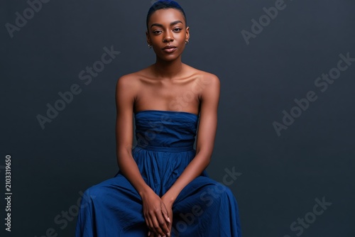 Studio portrait of an elegant woman in a strapless blue dress on a dark background for editorial portrait banner and fashion design