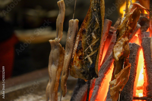 Close-up of Skewered Fish Grilling Over Open Charcoal Flames in a Traditional Japanese Robata Style