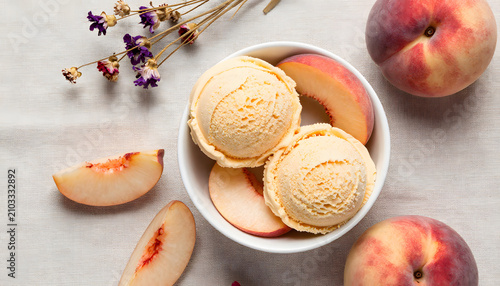 Overhead flat lay of two scoops of creamy peach ice cream served in a white bowl with fresh peach slices, whole ripe peaches and dried flowers on a light linen background, refreshing summer dessert, 