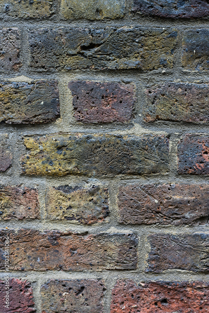 Fototapeta premium Aged and weathered multi colored rough texture brick wall background with dirt and grim