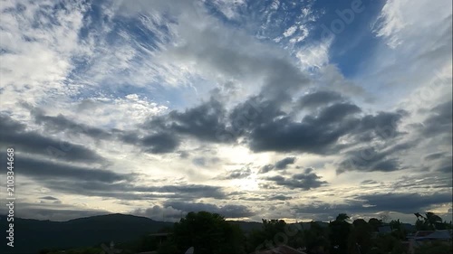 A cinematic time-lapse shot capturing dense, fast-moving clouds across the sky, partly covering the bright sun over the hilly landscape of Haflong, Dima Hasao, Assam, India. 4K UHD