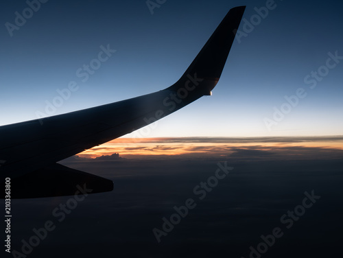фотографія Airplane Window View Above the Clouds at Sunset with Golden Sky and Scenic Aeria