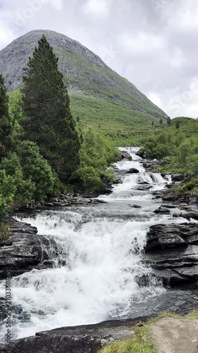 Crystal-clear water cascades down steep mountain slopes, forming beautiful waterfalls among rugged rocks and pristine Norwegian nature. Spectacular Scandinavian landscape with flowing water, dramatic 