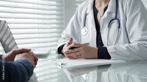 Doctor writing medical notes during a healthcare consultation, providing patient care, discussing diagnosis and treatment plan in a clinic office setting