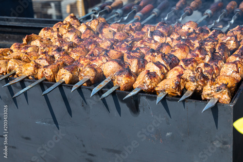 Marinated pork shashlik skewers grilling over charcoal on a large barbecue with smoke