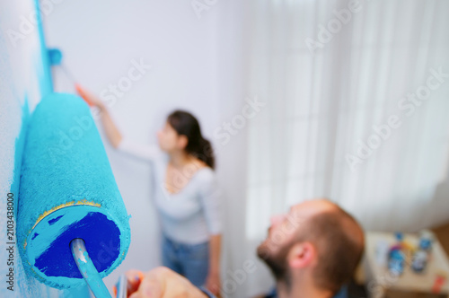 Foto Man painting blue wall in apartment in a home repair setting, connecting wall painting, decorating tools and apartment redecoration for a DIY makeover