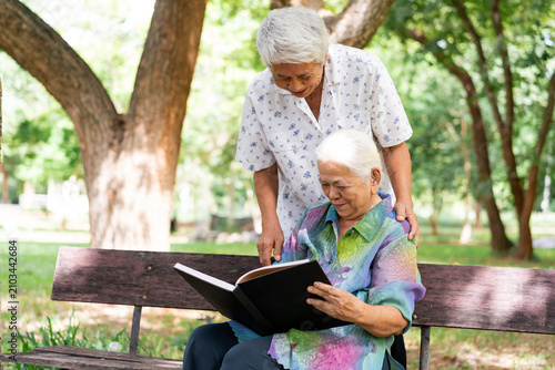 Obraz na płótnie Happy senior couple reading a book together on a sunlit park bench, enjoying ret