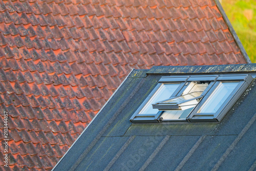 Bild auf Leinwand Modern roof window open on dark gray roof with old red tile roof background