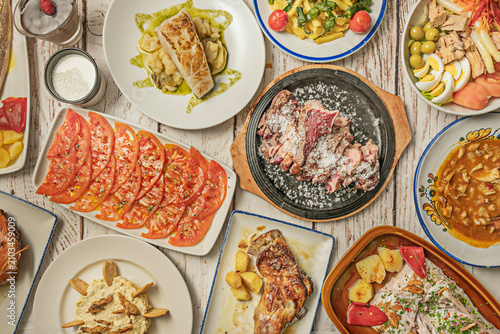 Spanish Tapas Table: Salt-Crusted Meat, Sliced Tomato Salad, Grilled Fish, Roasted Fish with Peppers and Salpicón