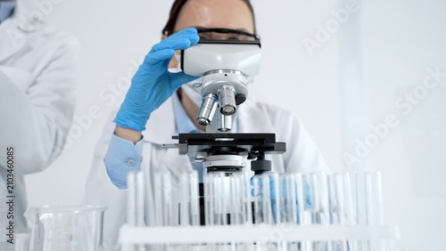 Фотография Young scientist wearing protective mask, safety glasses and gloves, observing sa