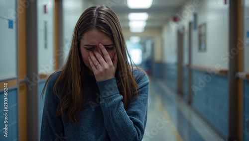 Young woman crying in a school hallway, feeling overwhelmed and distressed