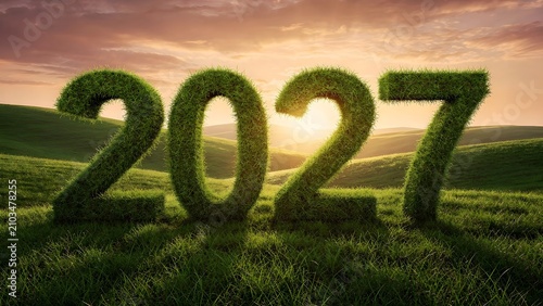Three dimensional numbers 2027 made of fresh green grass in a beautiful meadow landscape at sunset.