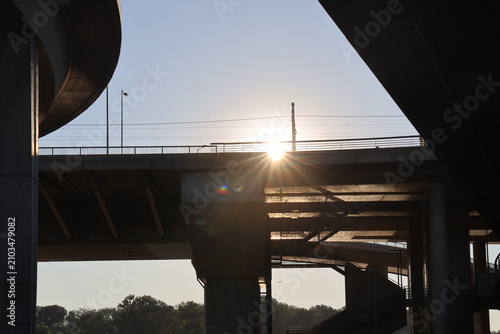 Fotografie Massive concrete girder bridge with round pillars crossing a calm at dawn, with