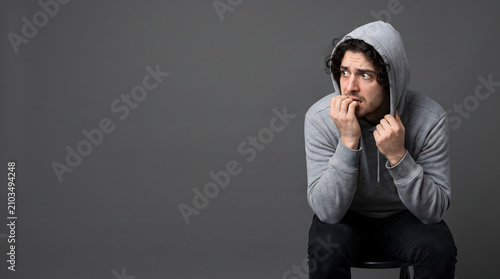 Young man wearing a hoodie looking anxious and worried.