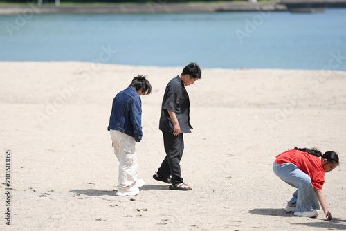Принти на полотні Three people explore a quiet beach beside calm waters