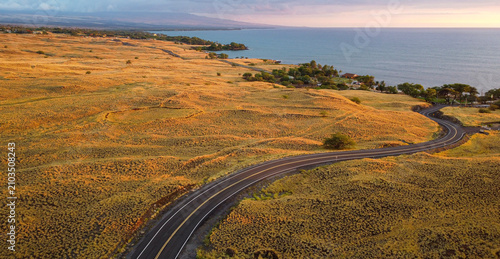 Drone aerial view of winding coastal road at golden hour near Spencer Beach Park, Big Island, Hawaii