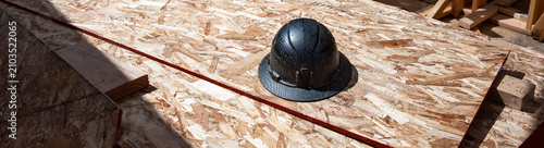 Fotografía Construction worker black hard hat, helmet on a stack of oriented strand board (