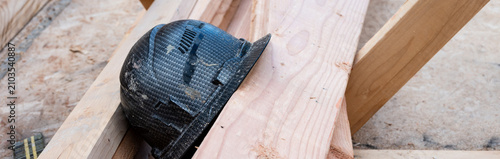 Foto Construction worker black hard hat, helmet, sitting on a pile of dimensional lum