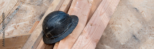Konstfotografi Construction worker black hard hat, helmet, sitting on a pile of dimensional lum