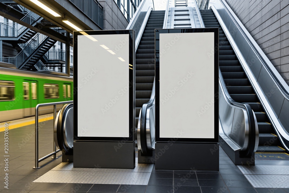 Obraz premium Two blank vertical digital screens stand in modern subway station next to moving escalator. Empty mockups offer space for commercial branding outdoor advertising campaign near train platform. Bright