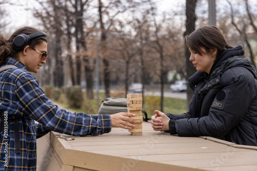 Foto A happy female student laughing and playing a board game with her classmate in a city park