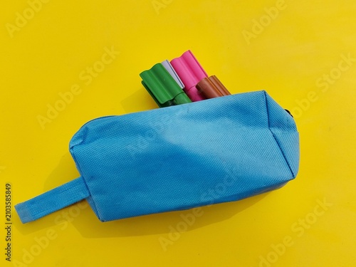 Fotografía Blue pencil case with colorful markers on yellow background, back to school, con