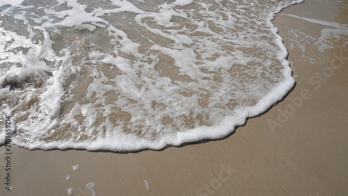 Canvastavla a closeup of small waves on the beach sand with soft foam