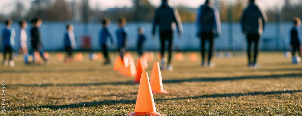Fototapeta premium Blurred photo of a children's soccer training session with cones and coaches