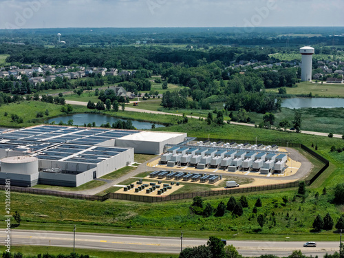 Aerial view of a data center with solar panels on the roof, AI center structure surrounded by roads and green countryside areas	