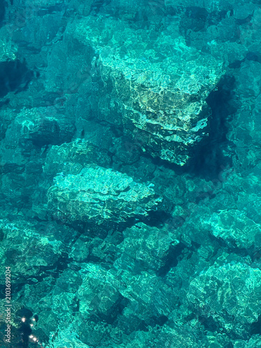 Azure blue sea water with rocky seabed vetical
