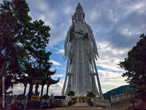 Bild auf Leinwand Statue of Quan Am in the courtyard of Linh An Pagoda in Da Lat, Vietnam, surrounded by traditional Buddhist architecture beneath a bright blue sky with tropical greenery