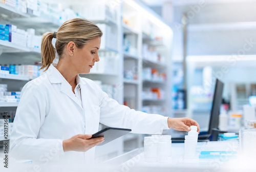 Pharmacist prepares prescription medication, verifying dispensing information during pharmacy workflow, supporting patient safety, medication management and healthcare services with copy space.