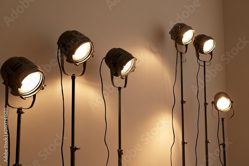 Stage lights illuminate a dimly lit room, casting warm glows and shadows