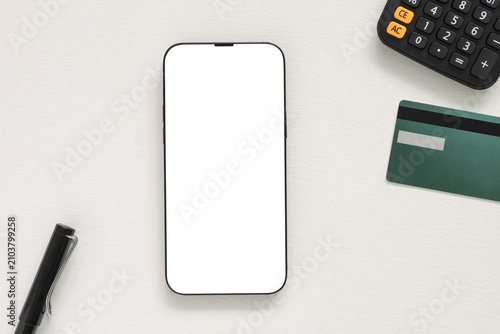 Blank smartphone screen mockup on a white desk with a pen, black calculator, and credit card. Top view flat lay template perfect for digital banking, finance, or ecommerce app design.
