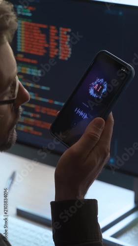 Over-the-shoulder view, of man holding smartphone, talking with AI chatbot app, asking questions, using artificial intelligence assistant for work and daily tasks on phone and computer. Vertical video